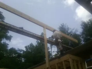 Carpenter setting a ridge beam over a new addition frame — Ice Dam Removal by Roofing Brothers in Del Valle