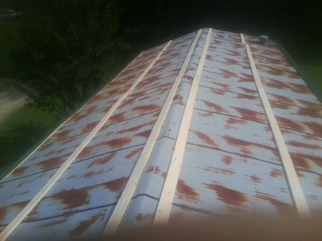 Rusted metal roof panels with new wood purlins before replacement — Storm Damage Roof Repair in Del Valle by Roofing Brothers