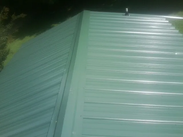 New green metal panels meeting at the ridge of a roof — Flat Roof Repair work by our crew in Del Valle