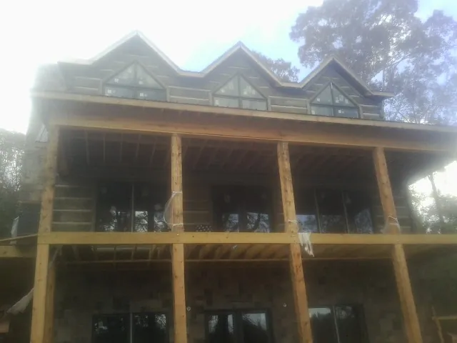 Dormers and porch framing on a large log home under construction — Roof Coating work by our crew in Del Valle