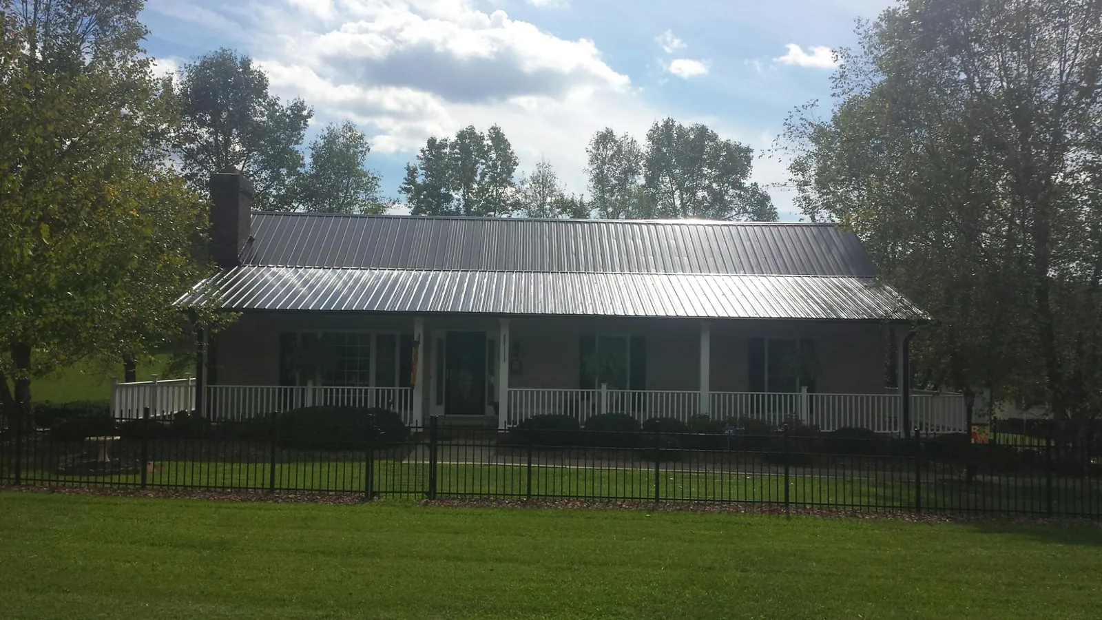 Gray metal roof on a brick ranch with a full width front porch — Gutter Guard Installation work by our crew in Del Valle