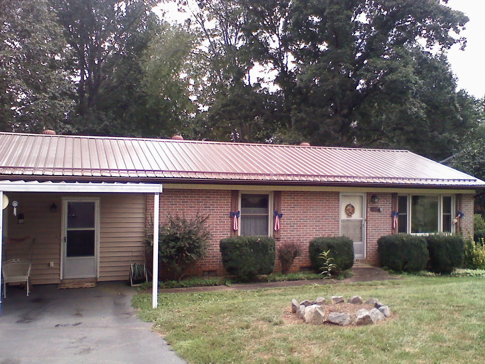 Bronze metal roof and carport on a brick ranch home — Roof Repair work by our crew in Del Valle