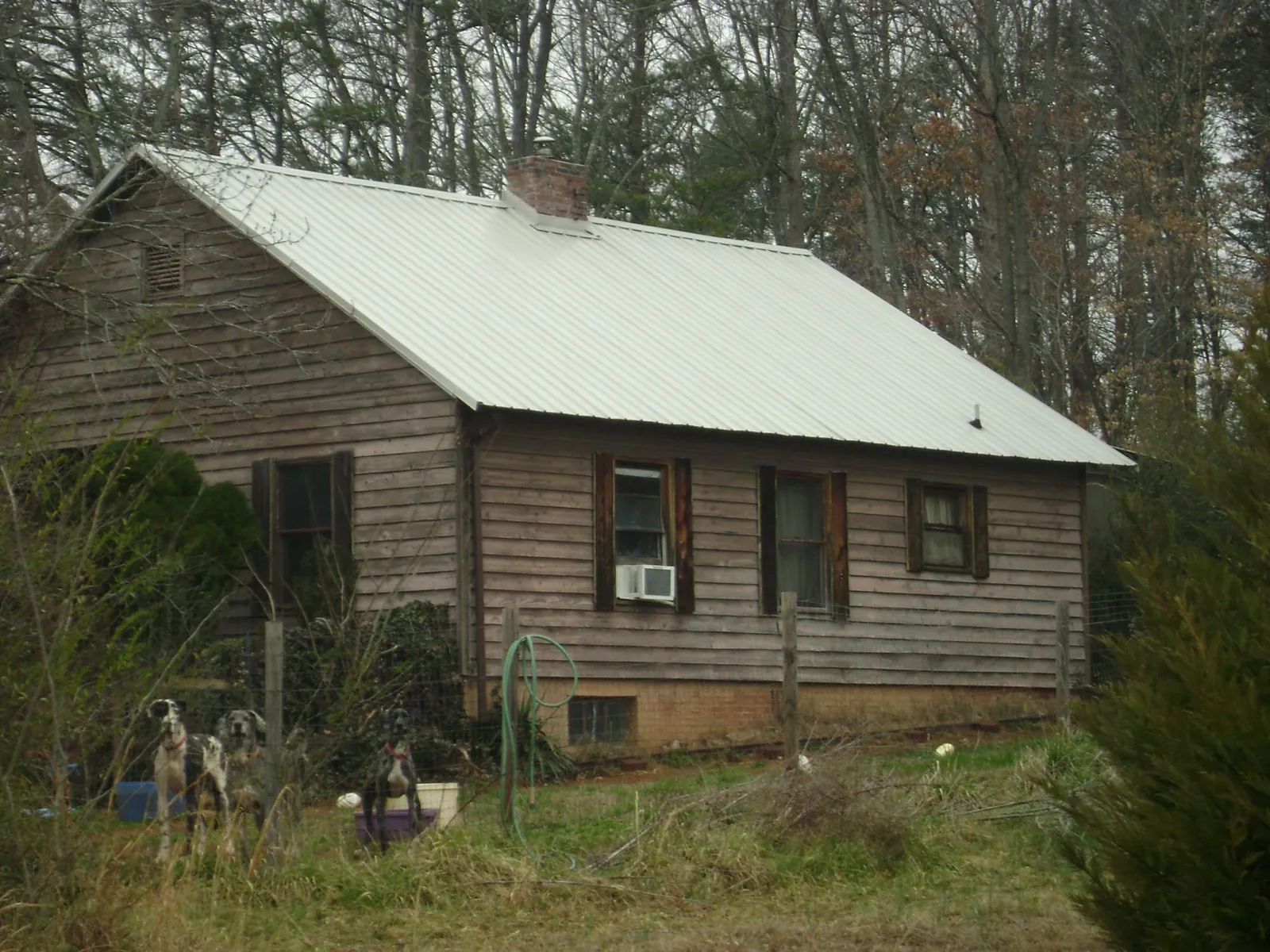White metal roof on an old wood sided farmhouse, from a Metal Roof Installation job in Del Valle