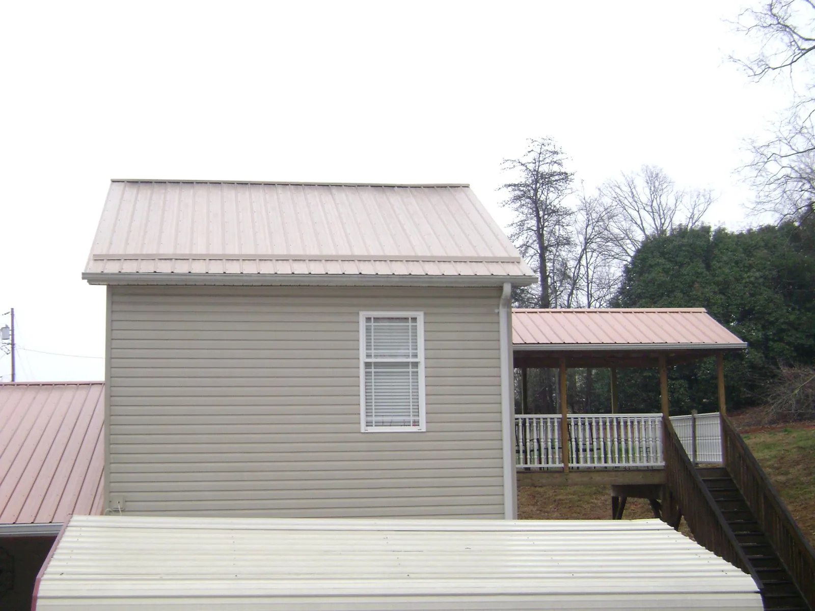 Tan metal roofs on a two story addition and attached porch, from a Roof Replacement job in Del Valle