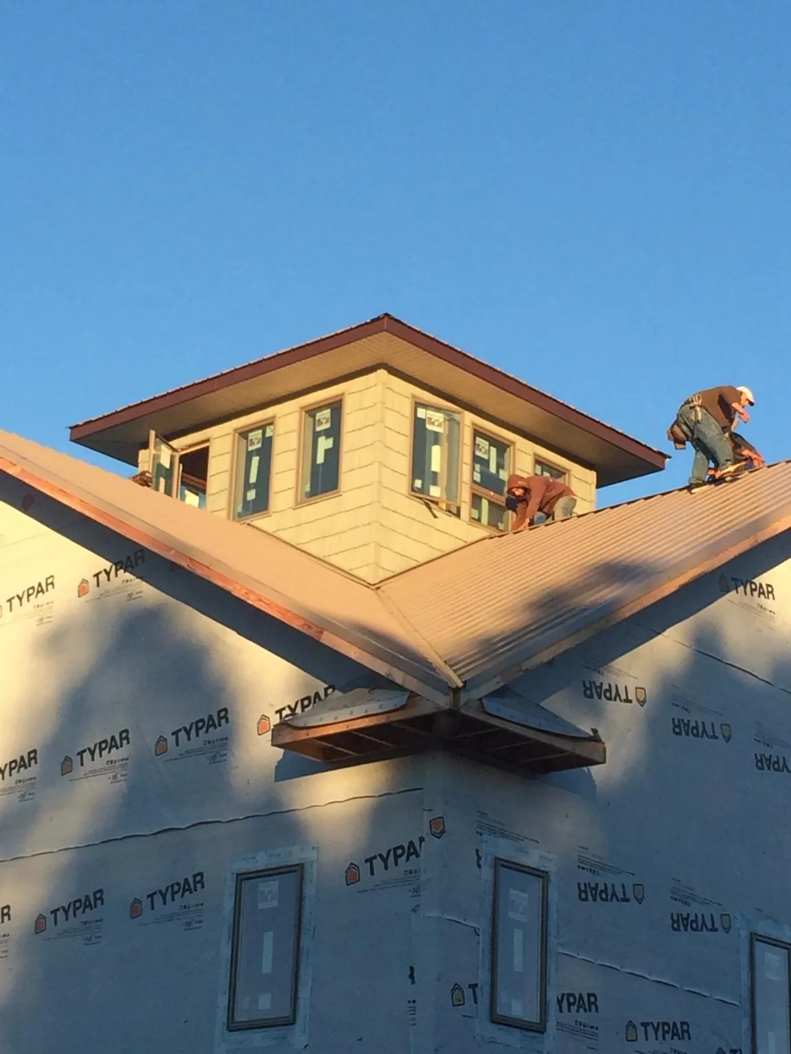 Roofers working around a rooftop cupola on a new metal roof at sunset — Roof Waterproofing in Del Valle by Roofing Brothers